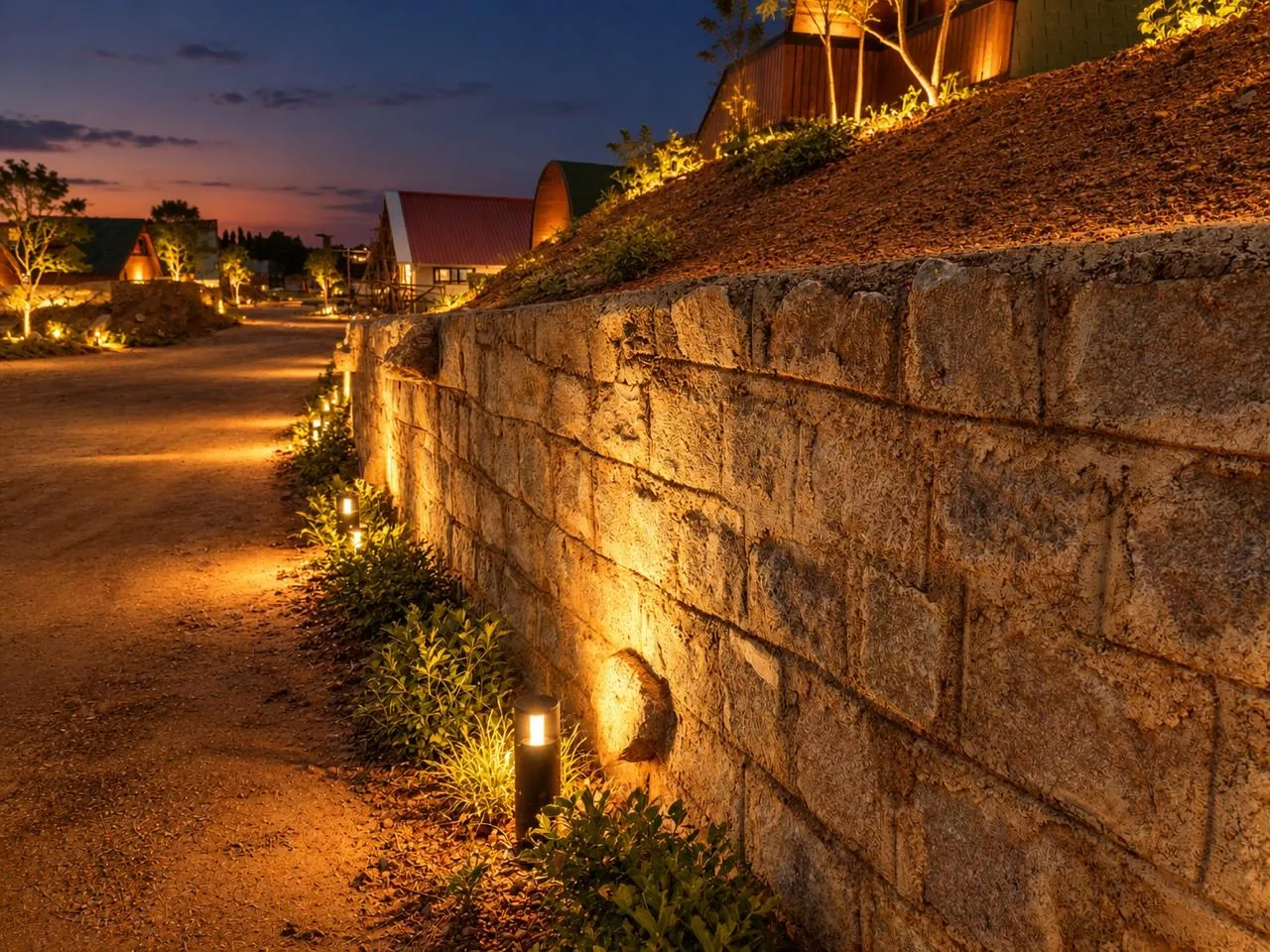 Lantern-lit garden path beside a hand-laid stone wall at Soulspire Resort
